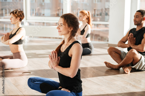 Group of people sitting in lotus pose at yoga studio
