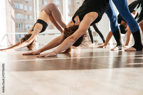 Group of people standing and doing yoga exercises barefoot