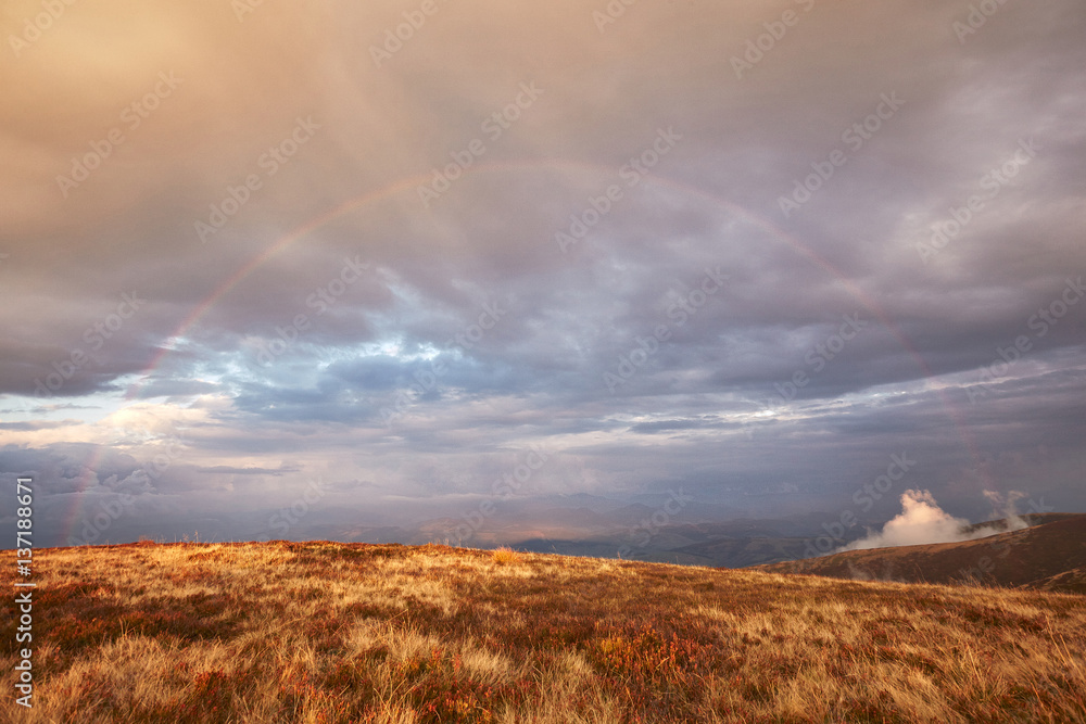 Rainbow in cloudy sky over the mountains
