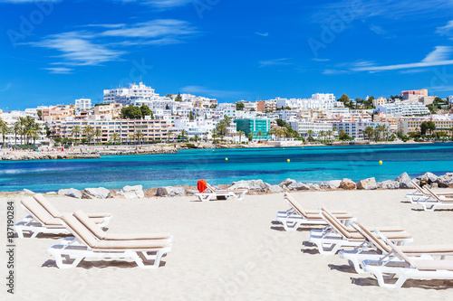 Sunbeds and beautiful city view on a beautiful beach in Ibiza, Spain.