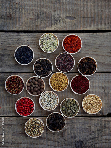 spices on a wooden background. Coriander, black pepper, paprika, mustard, turmeric, cumin, sumac, fenugreek, cloves, cubeb.