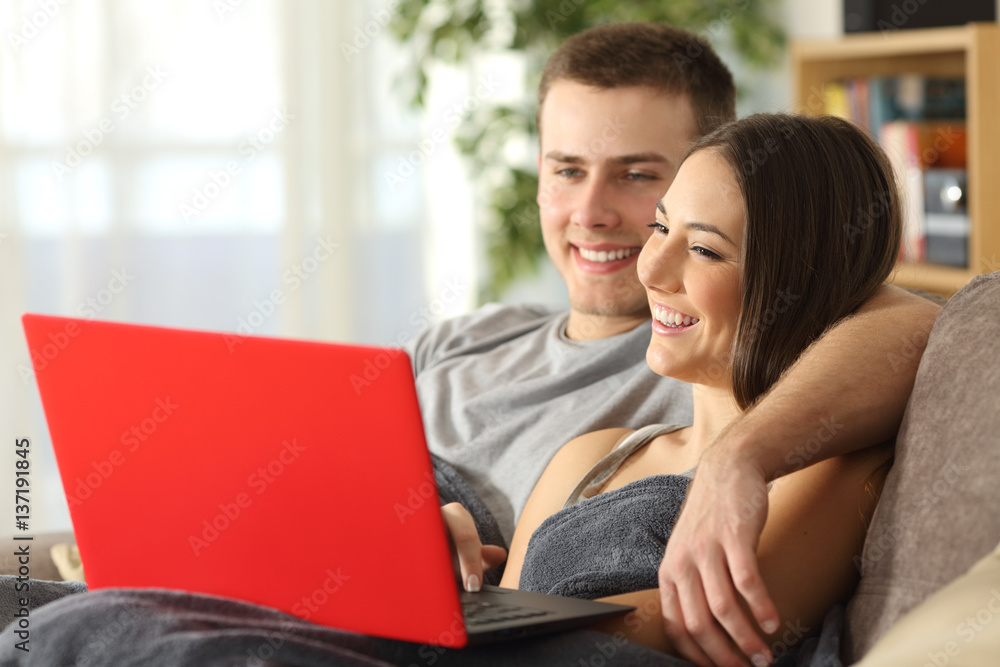 Couple browsing internet in a red laptop Couple browsing internet in a red laptop