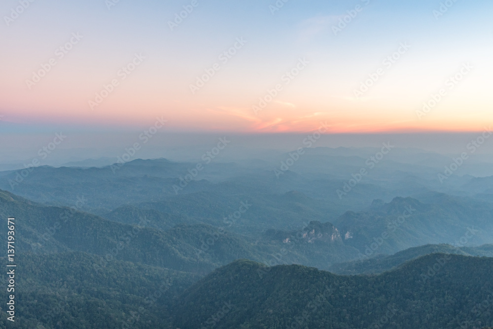 Fog covered forest and mountain at sunset.