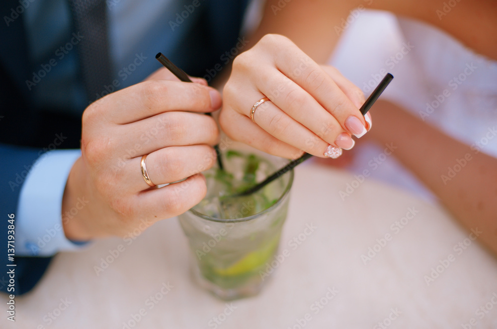 Obraz premium bride and groom holding wineglass with cocktail with lime