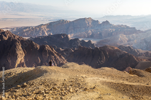 Woman backpacker tourist sitting resting mountain edge desert landscape.