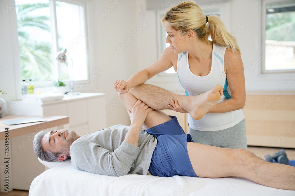 Obraz premium Physiotherapist stretching patient's leg