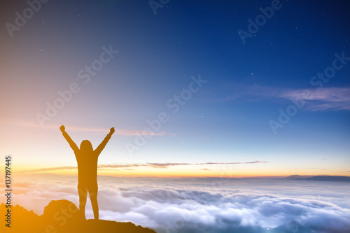 silhouette woman rising hands on mountain at morning with cloud fog