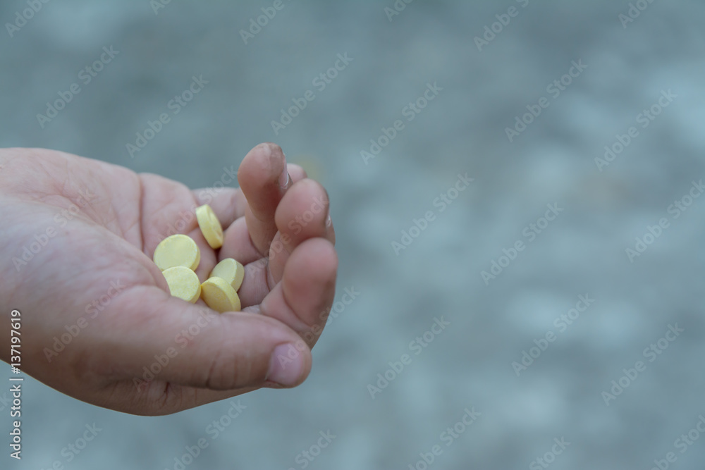 yellow round pill in dirty children hand yellow round pill in dirty children hand