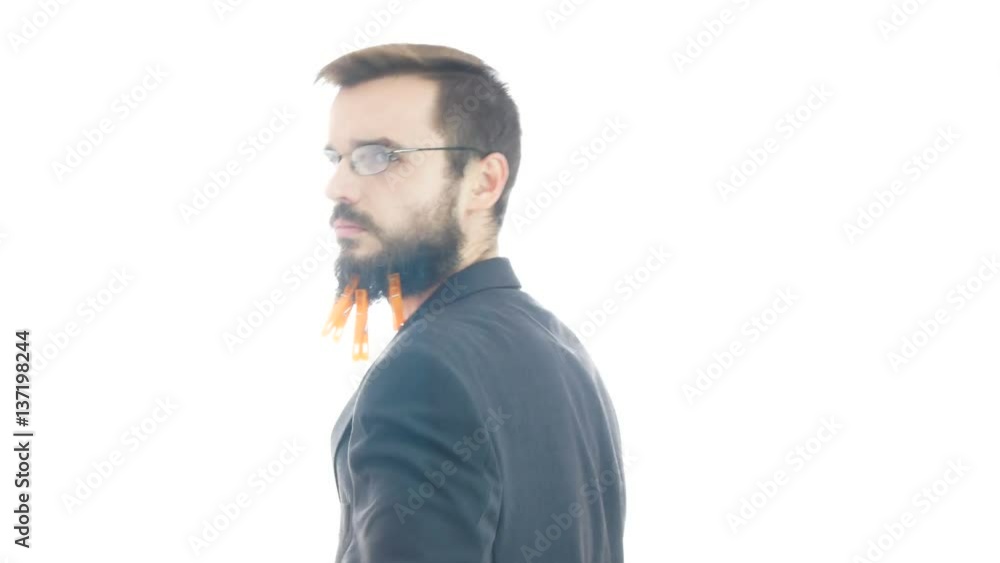 Serious bearded man in suit walking with clothespins on his beard and looking at you, studio isolated on white background. Serious bearded man in suit walking with clothespins on his beard and looking at you, studio isolated on white background.
