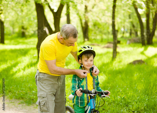 grandfather wears a bicycle helmet to his grandson