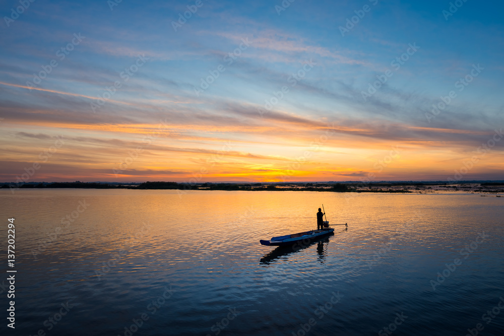 fisherman on long tail boat in the lake with sunrise background