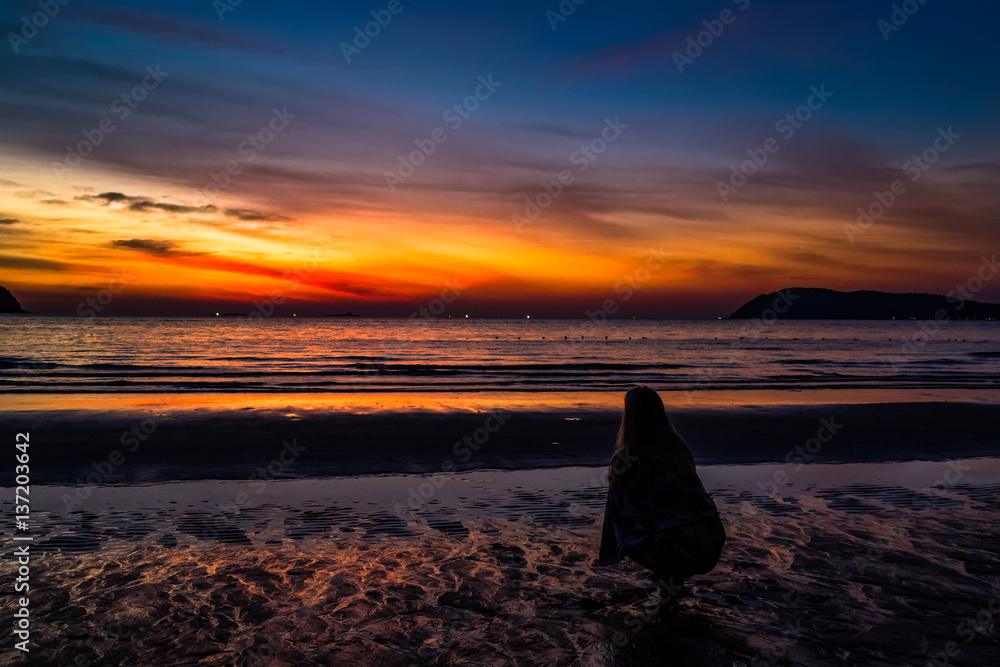 Naklejka premium Sunset in Pantai Tengah beach, Langkawi, Malaysia. Girl looking a the last traces of light in the sky.