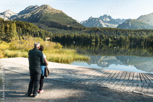 healthy and vital senior couple standing on hike and watching beautiful mountain view