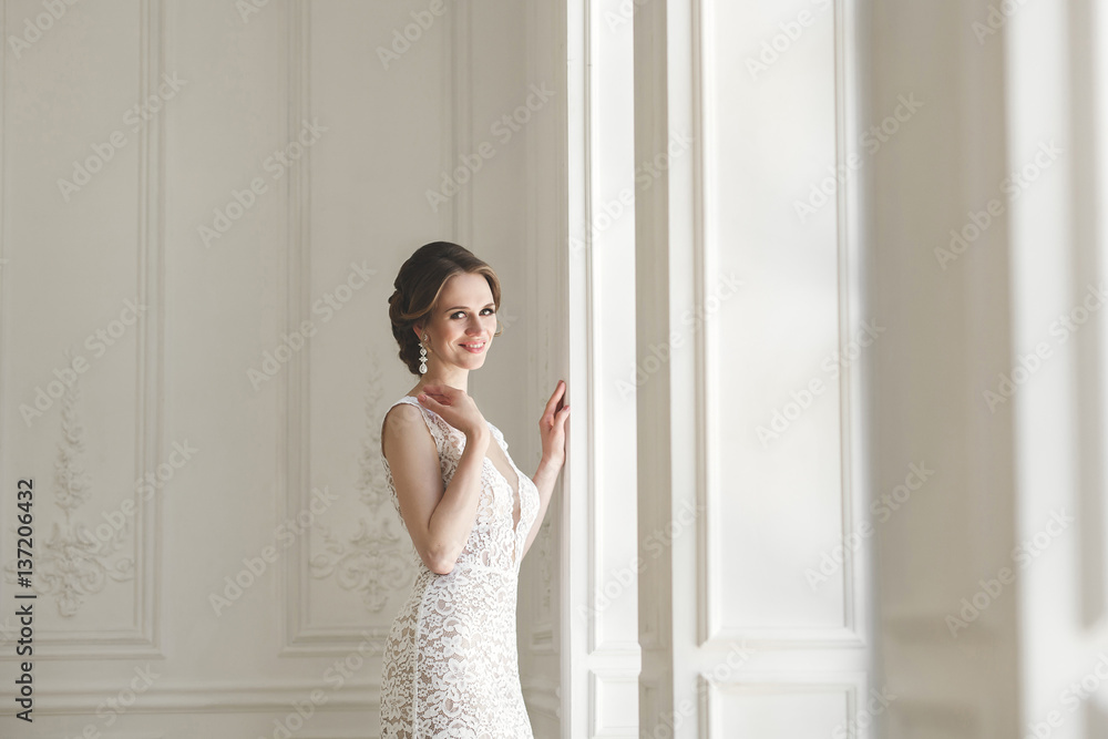 Beautiful bride posing in wedding dress in a white photo Studio. Mirror. Sofa. Bouquet. The door. Chandelier. Beautiful bride posing in wedding dress in a white photo Studio. Mirror. Sofa. Bouquet. The door. Chandelier.