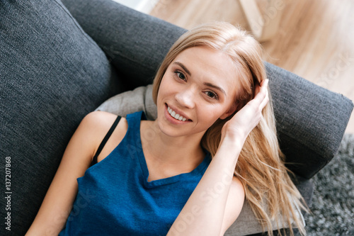Happy attractive young woman lying on sofa at home