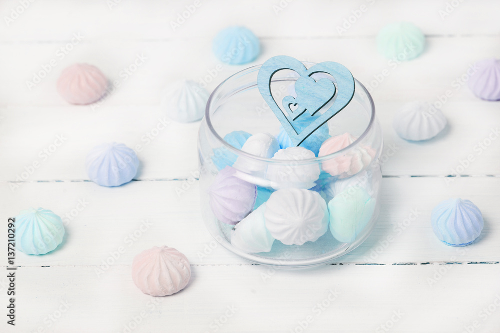 Color zephyrs and wooden figure of heart in glass jar on white wooden table. Concept of St. Valentine's Day Color zephyrs and wooden figure of heart in glass jar on white wooden table. Concept of St. Valentine's Day