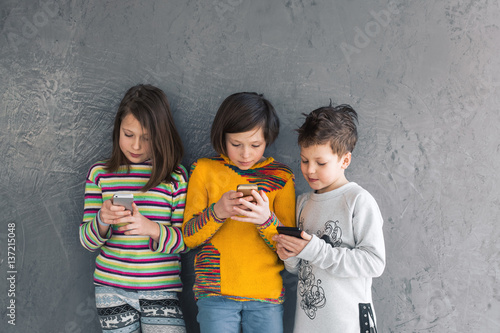 Group of young girls and a boy playing in the phone, smiling and laughing.