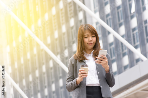 Business woman using a communication tool. The background is a building in the city.