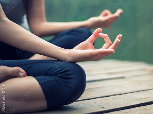 Fototapeta Naklejka Na Ścianę i Meble -  Close up hand. Woman do yoga outdoor. Woman exercising yoga at the nature background, select focus..