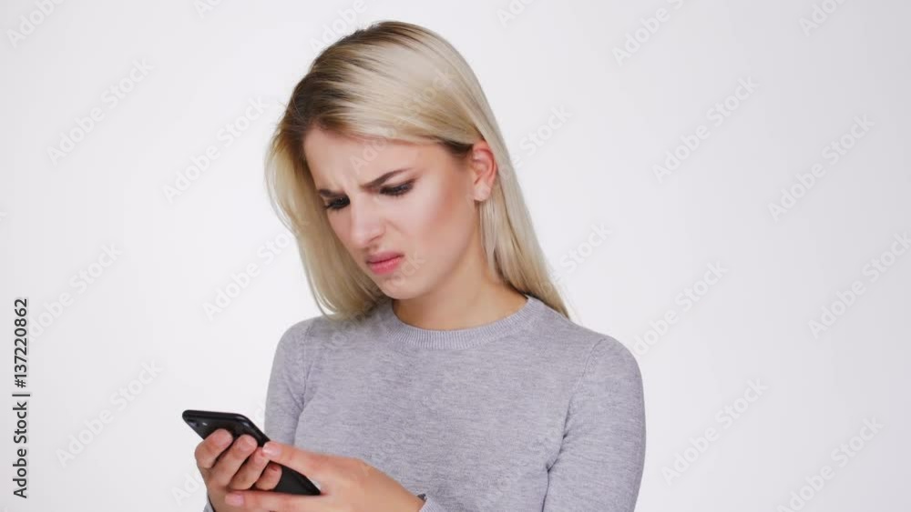 Irritated Woman in gray sweater writing message on phone Irritated Woman in gray sweater writing message on phone