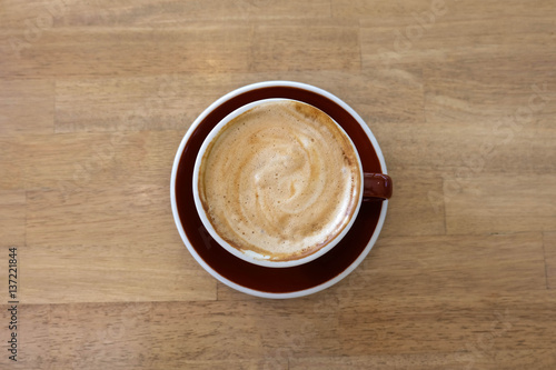 A cup of coffee with latte art in a brown cup on wooden table background