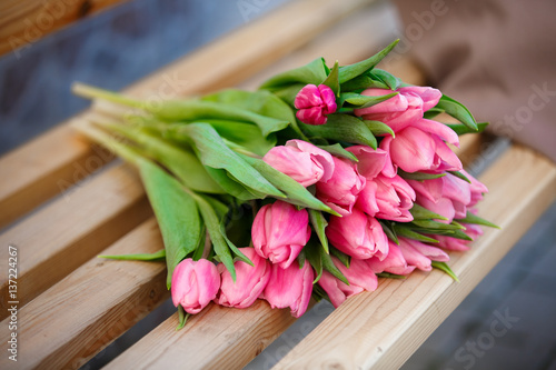 Fototapeta Naklejka Na Ścianę i Meble -  Fresh pink tulips flowers on bench outdoors spring 