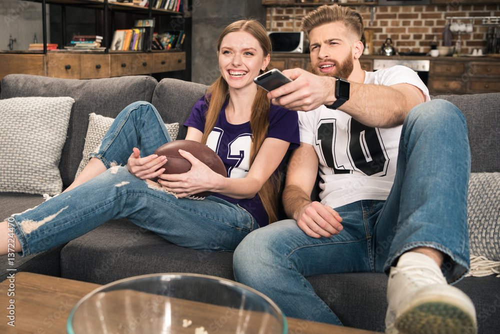 portrait of happy stylish couple watching sports game at home portrait of happy stylish couple watching sports game at home