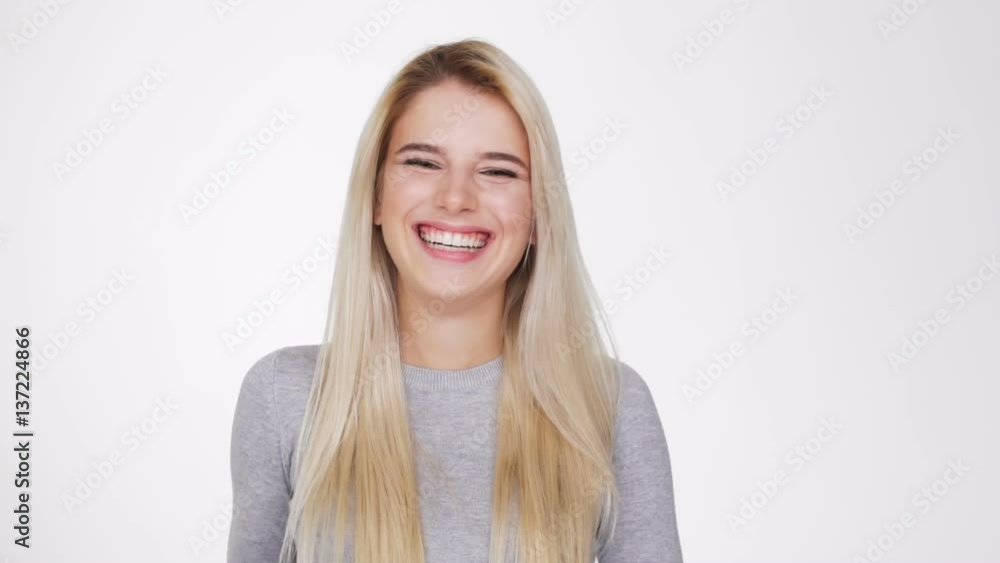 Laughing Blonde woman in sweater looking at camera and covering her mouth Laughing Blonde woman in sweater looking at camera and covering her mouth