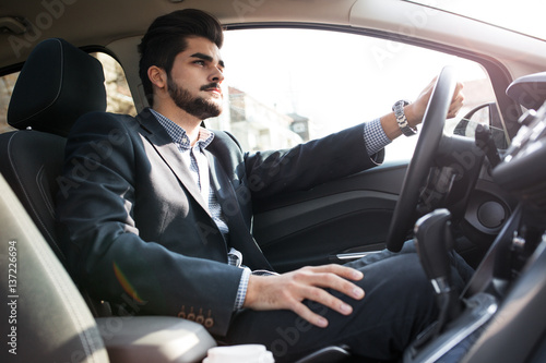 The handsome businessman, driving with a sense of urgency, hurries to a crucial business meeting. © BalanceFormCreative