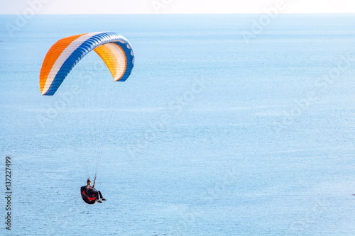 Sitting skydiver with a parachute flying over the sea with the horizon