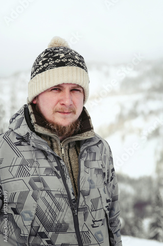 Portrait of bearded man in grey ski jacket posing on the hill © syrotkin
