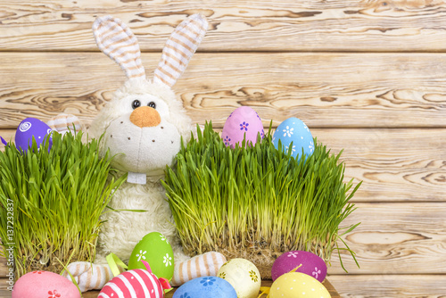 Toy little Easter bunny and Easter eggs on green grass. Easter concept. photo