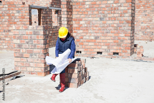 Foto Site manager looking at blueprint on construction site