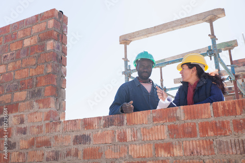 Woman and builder talking on construction site photo