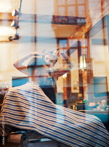 View through window of hairdresser cutting customer's hair photo