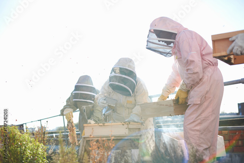 Male and female beekeepers using bee smoker on city rooftop photo