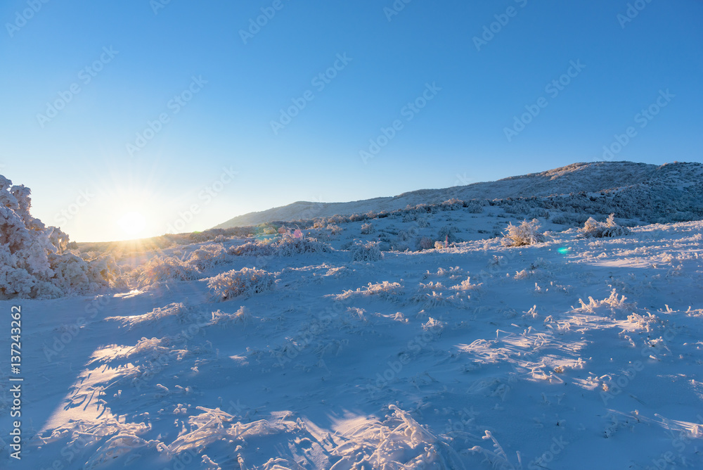 Sun hides behind the frozen mountain, winter mountainscape