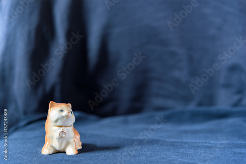 Sculpture lying cat with a collar with a diamond on black background.