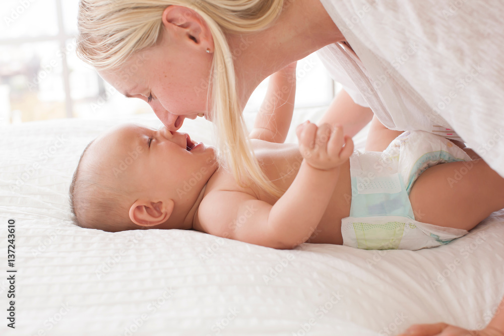 Mid adult woman nose to nose with baby son lying on bed Mid adult woman nose to nose with baby son lying on bed