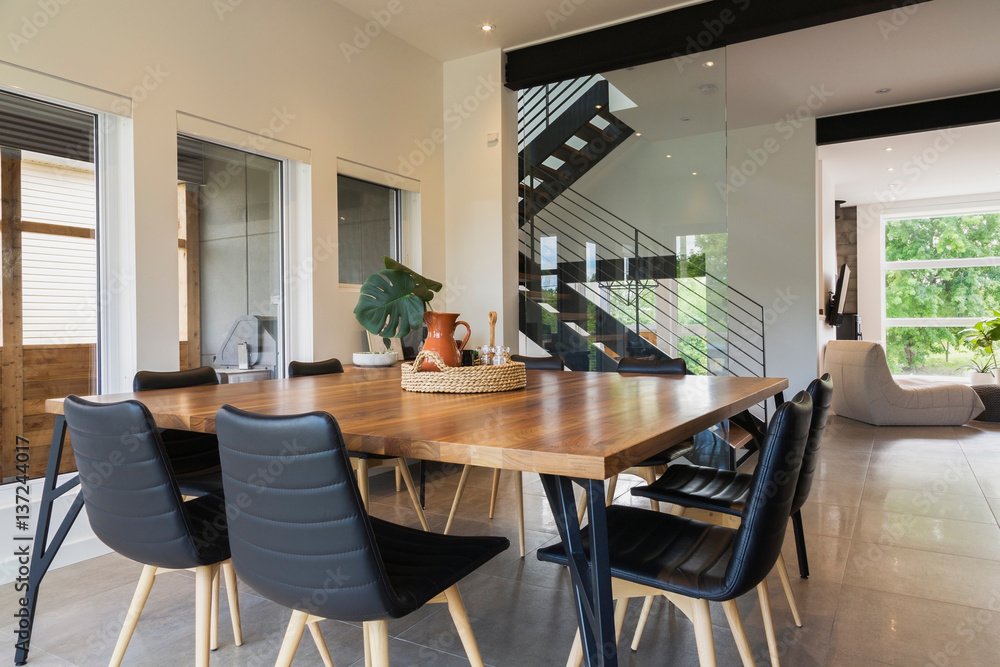 American walnut wood dining table and black leather sitting chairs with ash  wood legs in the dining room inside a modern cube style home, Quebec, Canada  Photos | Adobe Stock