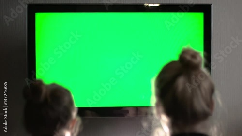 Two young long haired blond watching green TV screen and laughing