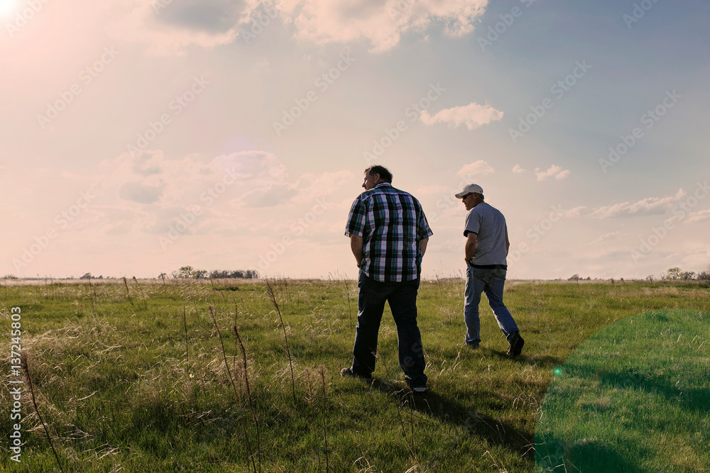 Two mature men walking in field landscape near Hastings Nebraska, USA Two mature men walking in field landscape near Hastings Nebraska, USA
