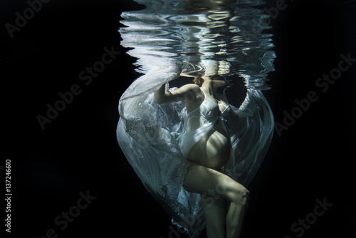Pregnant woman swimming underwater