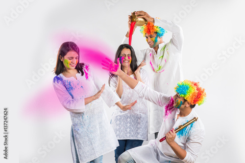 good looking indian people celebrating holi festival with mobile phones, colours, sweets and pichkari, isolated over white background