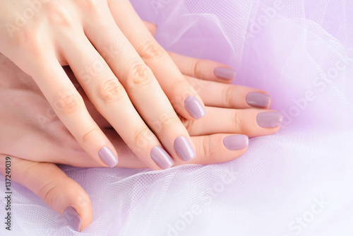 Closeup of hands of a young woman with pink manicure on nails against the background of a pink vei