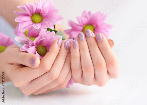 Hands of a woman with pink manicure on nails and pink flowers