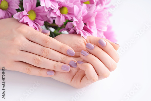 Hands of a woman with pink manicure on nails and pink flowers © nmelnychuk