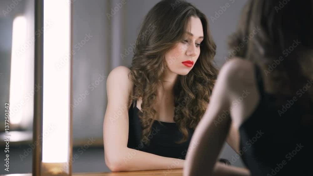 Brunette woman using smartphone near the mirror and wipes his lips Brunette woman using smartphone near the mirror and wipes his lips