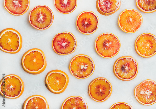 Natural fruit pattern concept. Fresh juicy blood orange slices over light marble table background, top view
