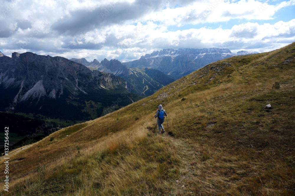 Wanderin unterwegs auf Bergwiese in traumhafter Bergkulisse in Gröden / Südtirol